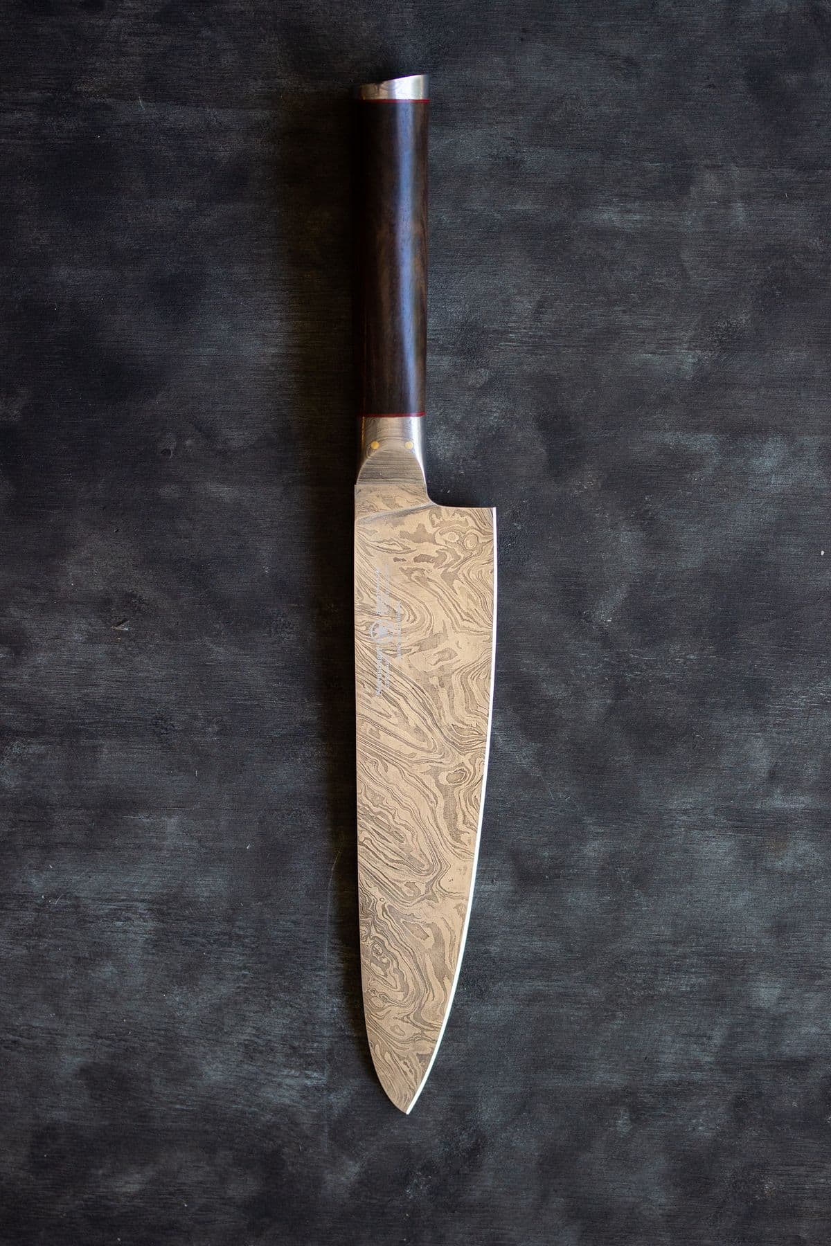 Damascus steel chef knife on a dark surface