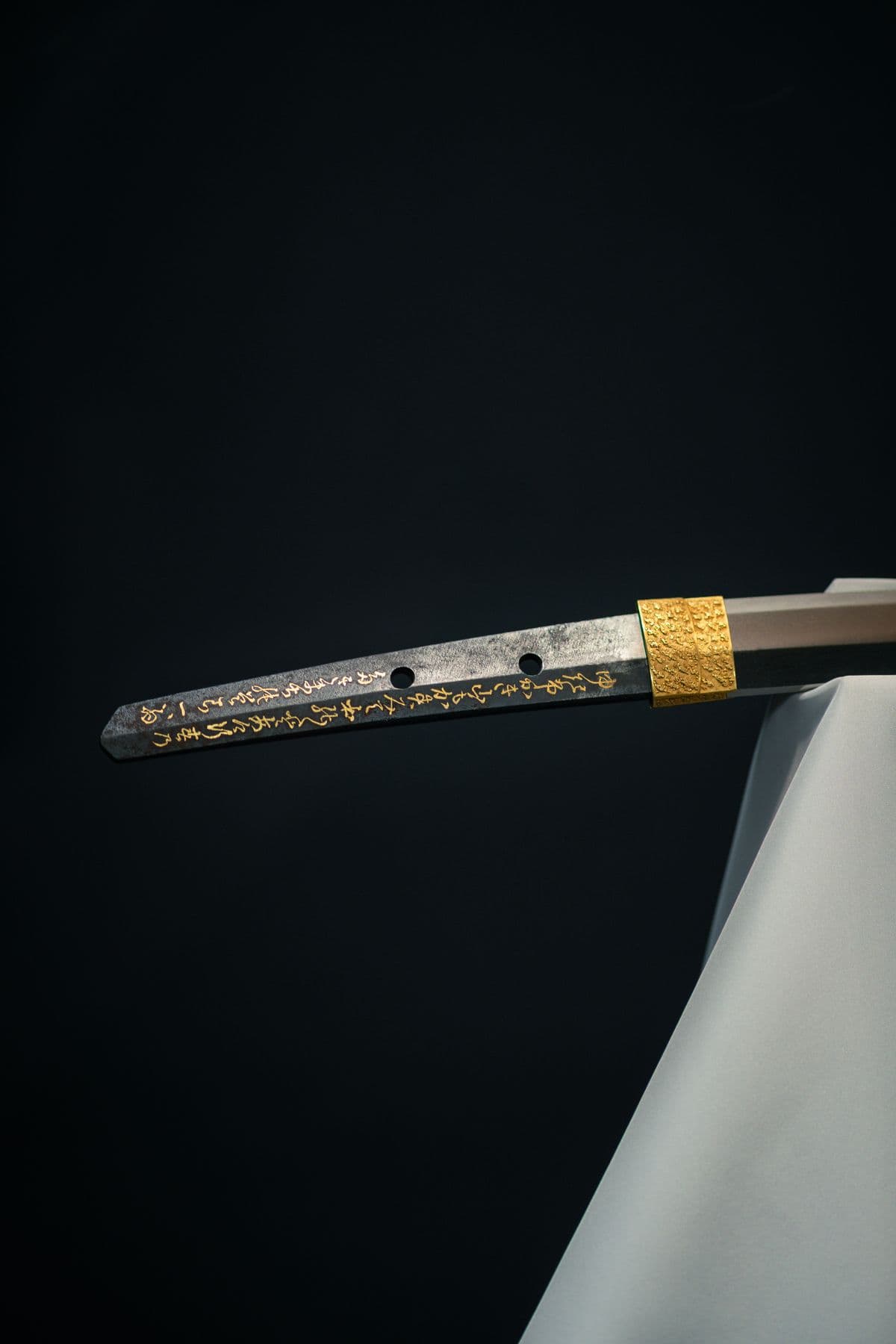 Detail of a sword tang and fittings on a dark background